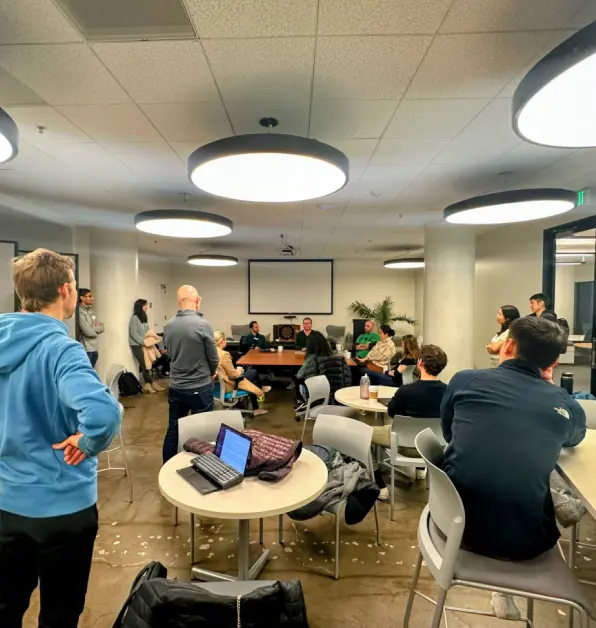 Attendees meeting in a workspace with tables and laptops